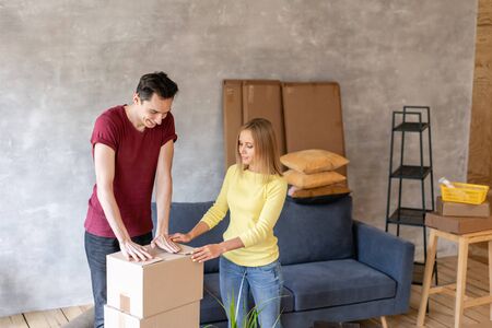 Happy people packing cardboard box, concept moving house. Young couple moving to a new apartment together. Relocation conceptの写真素材