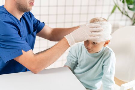 Sports injury. Doctor makes bandage on head patient, in the hospital.の写真素材