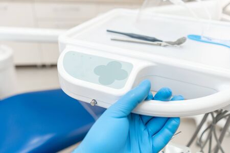 The hand of the dentist in the glove presses the control buttons of the chair.. Dental work in clinic. Operation, tooth replacement. Medicine, health, stomatology concept.の写真素材