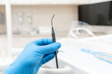 The hand of the dentist in the glove holds tool mirror. Stomatological instrument in the dentist clinic. Dental work in clinic. Office where dentist conducts inspection and concludes.の写真素材