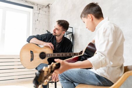 A professional musical teacher listening sounds making by his student by playing guitarの写真素材