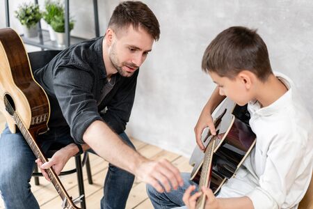 A personal tutor explains to his young student how to play studied chord correctly. Musical education at homeの写真素材