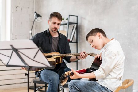 Two brothers of different ages rehearsing a melody from a sheet musicの写真素材