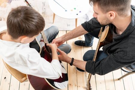 A personal tutor explains to his young student how to play studied chord correctly. Musical education at homeの写真素材