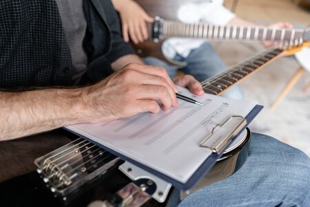 A personal tutor writes notes on music sheet for his student and explain how to play them.の写真素材