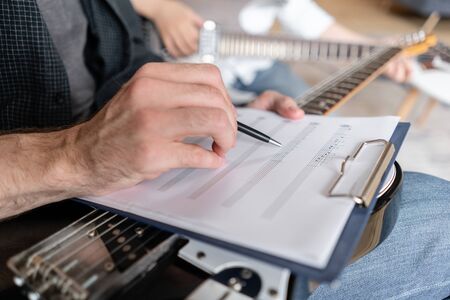 Older brother explains to his younger one how to use notes on music sheets on an exapmpleの写真素材