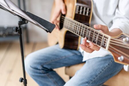 Focused kid playing his favorite melody on acoustic guitarの写真素材