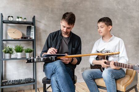 Young student listening his tutors lecture about playing elecrric guitar.の写真素材