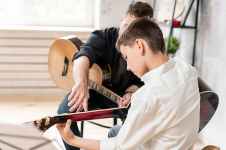 A personal tutor explains to his young student how to play studied chord correctly. Musical education at homeの写真素材