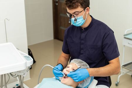 Yoing boy got his tooth drilled by stomatologist wearing gloves and microscope glassesの写真素材