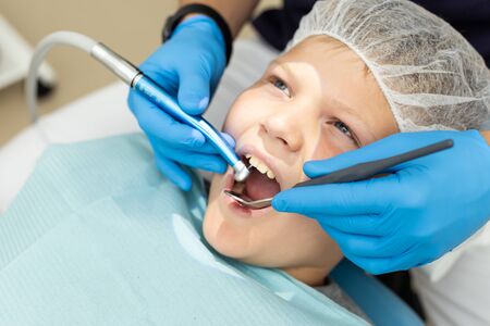 Little boy holds his mouth open while dentist drills his toothの写真素材