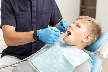 Young boy hold his mouth open while his doctor mothwashing itの写真素材
