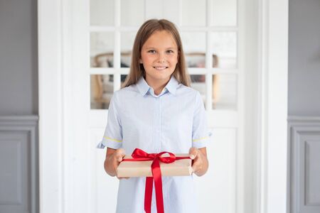 A young girl in light blue shirt holds out a gift to the camera. Selective focusの写真素材