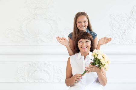 An elderly woman smiles and enjoys the mothers day surprise of her granddaughter. Selective focusの写真素材