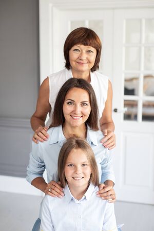 Three smiling woman's of different ages stands in a row. Selective focusの写真素材
