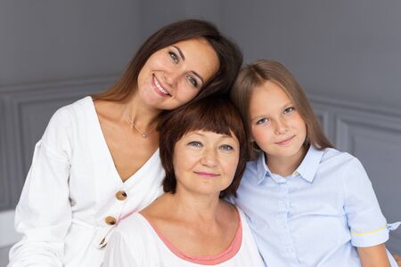 Three woman of different ages hug each other and smileの写真素材