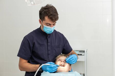 Little boy is laying on dentist chair and got his teeths drilled by professional stomatologistの写真素材
