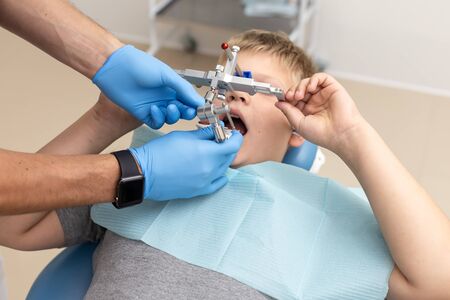 Little boy lays on chair while dentist fixing up orthodontic archの写真素材