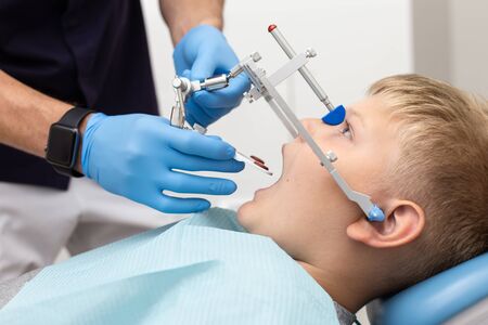 Little boy keep his mouth wide open while his dentist setting up orthodontic archの写真素材