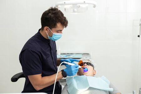 Dentist wearing blue gloves check-up teeth of little boyの写真素材