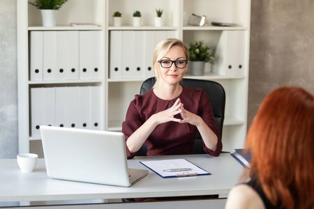Blonde manager in red dress listens to her subordinate. Selective focusの写真素材