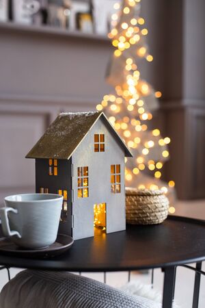 Closeup of paper house and two empty cups on a black table and a fir of wooden planks on backgroundの写真素材