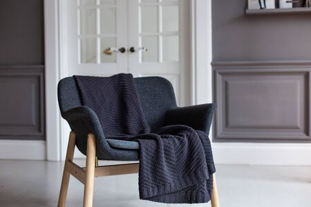 Armchair with black plaid laying on it stands in living roomの写真素材