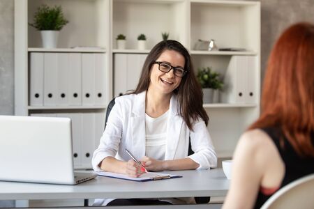 Smilng manager talks with her new employee and making notes. Selective focusの写真素材
