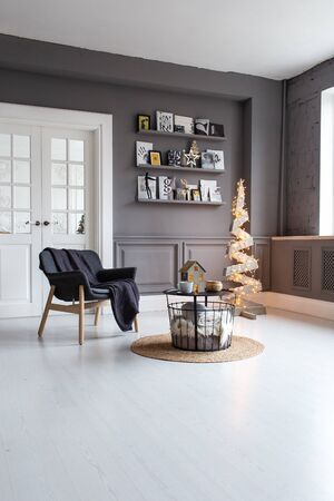 Nizhniy Novgorod, Russia - November 11, 2019: Photo studio 2.8. Living room with chair, table, shelf and wooden tree decorated with garlandのeditorial素材