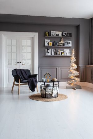 Nizhniy Novgorod, Russia - November 11, 2019: Photo studio 2.8. Living room with chair, table, shelf and wooden tree decorated with garlandのeditorial素材