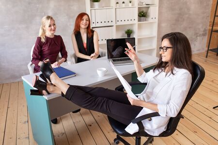 Two workers sits in cabinet of their boss and talk with herの写真素材