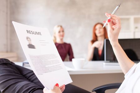 Closeup of resume in hands of HR with two women on background. Selective focusの写真素材