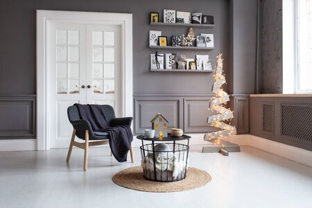 Nizhniy Novgorod, Russia - November 11, 2019: Photo studio 2.8. Living room with chair, table, shelf and wooden tree decorated with garlandのeditorial素材