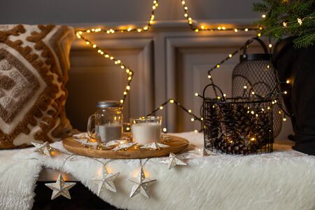 Tray with jar of milk and mug placed on bench next to garland star and pillowの写真素材