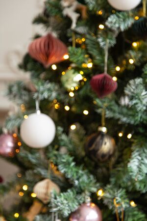 Blured photo of shiny toys and garland hanging on fir branchesの写真素材