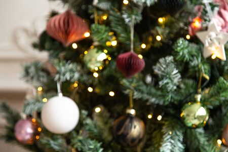Blured photo of shiny toys and garland hanging on fir branchesの写真素材