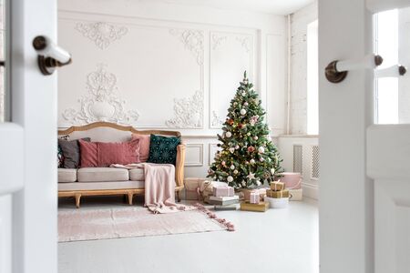 White sofa standing next to christmas tree surrounded by gift boxes. Selective focusの写真素材