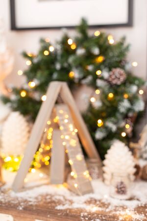 Blurred photo of pyramid made of wood and a few cones stand on the chest of drawers in front of the wreathの写真素材