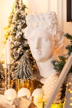 Statue of head surrounded by firs, cones and candles standing on wooden dresserの写真素材