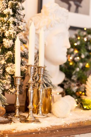 Closeup of candles in candlekeeps and statue of head standing on wooden desk. Selective focusの写真素材