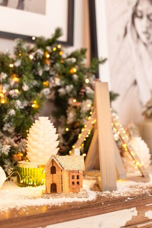 Pyramid made of wood, little house and few cones stand on the chest of drawers in front of the wreathの写真素材
