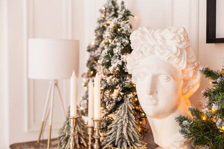 Plaster head statue on background of candels and christmass tree. Selective focusの写真素材