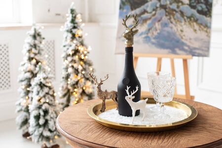 Nizhniy Novgorod, Russia - November 13, 2019: Photo studio 2.8. Festive still life consisting of a bottle of champagne, figures of deer, easel and spruce in the backgroundのeditorial素材