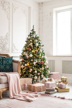 Lots of gif boxes lay next to sofa and decorated with garland and toys christmas tree. Selective focusの写真素材