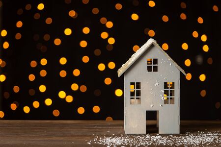 Paper toy house standing on wooden table with garland on background. Selective focusの写真素材