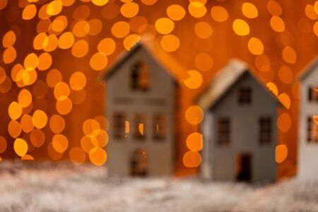 Blured photo of paper houses standing in a row on wooden table, covered in snowの写真素材