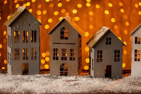 Paper houses standing in a row on wooden table, covered in snow. Selective focusの写真素材
