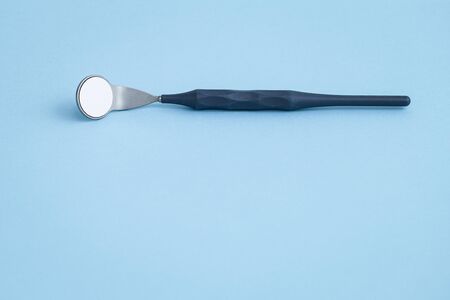 Dental mirror laying on light blue backgroundの写真素材
