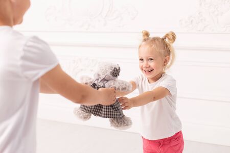 Little blond girl smile and accept gift from her sister with enjoyment. Soft focus.の写真素材