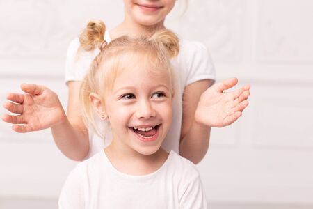 Two little blond girls fooling around and play with each otherの写真素材